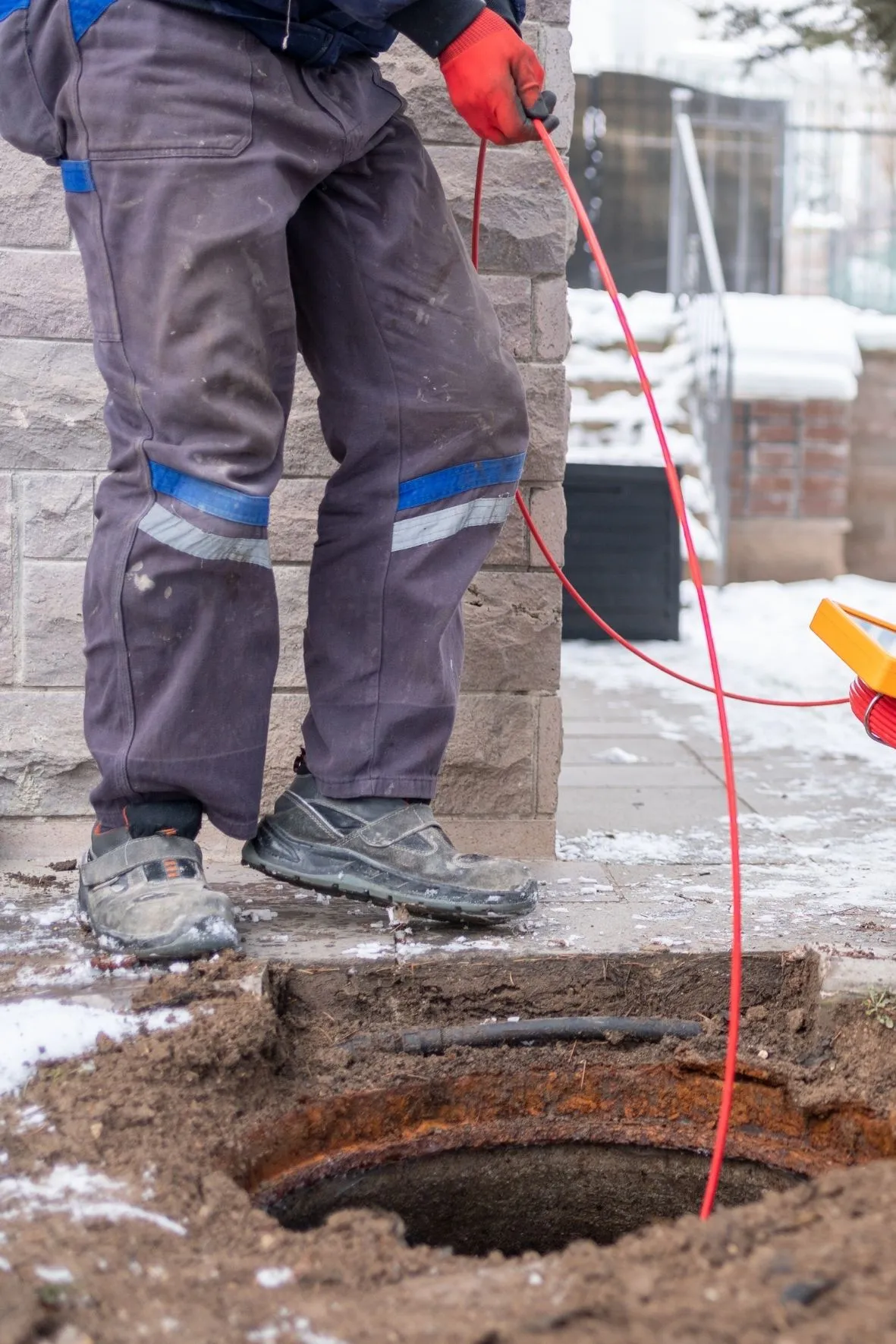 Technicien en plomberie effectuant un débouchage de drain à l’intérieur d’une maison à Terrebonne